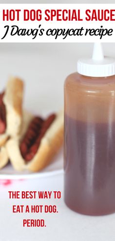 hot dog sauce in a plastic bottle on a plate next to some hotdogs