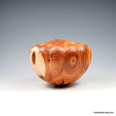 a wooden bowl sitting on top of a white table next to a gray wall in the background