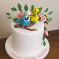 two birds sitting on top of a white cake