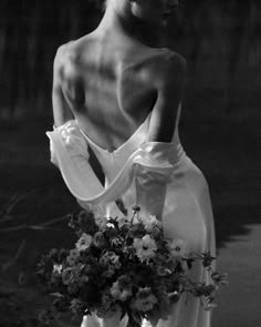 a black and white photo of a woman in a dress with flowers on her back