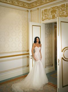 a woman in a wedding dress is standing by an open door