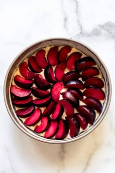 plum cake with streusel topping in a metal bowl on a marble counter top