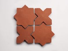 four pieces of red clay sitting on top of a white surface, each with different shapes and sizes