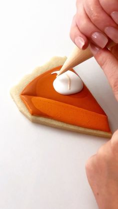 a woman is decorating an orange and white slice of pie with icing on it