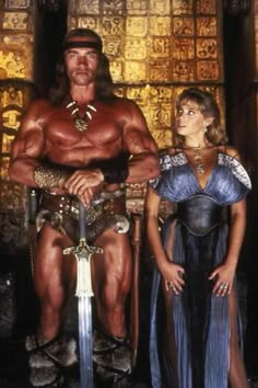 a man and woman standing next to each other in front of a giant, muscular man