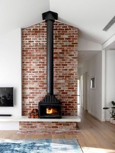 a living room with a brick wall and a fireplace in the center, surrounded by hardwood floors