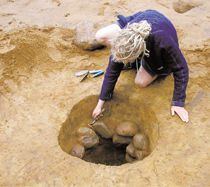 a woman is digging into a hole in the ground