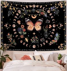 a large tapestry hanging on the side of a bed covered in flowers and butterflies with lights