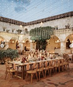 an outdoor dining area with tables and chairs, lights strung from the ceiling and potted plants