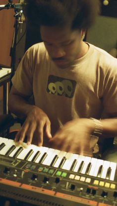 a young man playing an electronic keyboard in front of a microphone and sound equipment set up