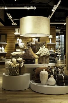 a room filled with lots of different types of pillows and blankets on top of white pedestals