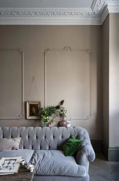 a living room with a couch, table and potted plant on the wall in front of it