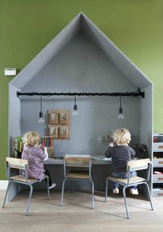 two children are sitting at a table in front of a house shaped like a tent