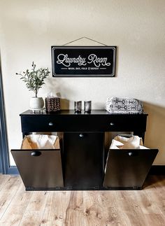 a black cabinet with two bins underneath it and a sign on the wall above it