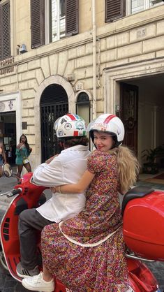 two people riding on the back of a red scooter