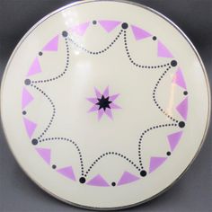 a white plate with purple and black designs on the bottom, sitting on a table