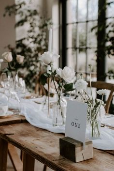 the table is set with white flowers and place cards for guests to sit down at