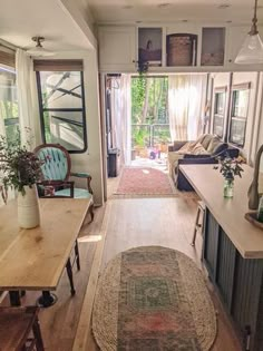 a living room filled with furniture next to a kitchen and dining room table in front of an open door