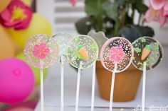 four lollipops with flowers and carrots on them sitting in front of some balloons