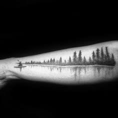 a black and white photo of a man's arm with trees on it