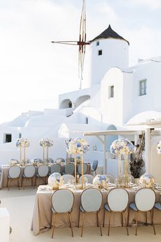 an outdoor dining area with tables, chairs and umbrellas set up for a formal function