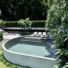 an empty swimming pool in the middle of a garden with lounge chairs and trees around it