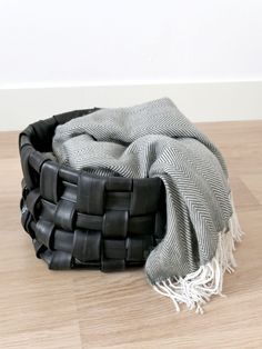 a black and white blanket sitting on top of a wooden floor next to a basket