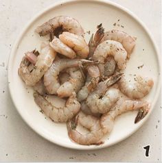 a white plate topped with shrimp on top of a table