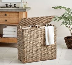 a wicker laundry hamper with towels in it and a potted plant next to it