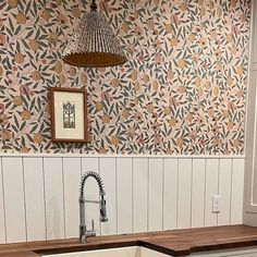 a kitchen with a sink, faucet and wooden counter top under a light fixture