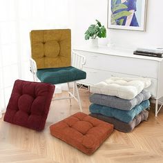 four different colored chairs and foot stools in a room