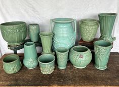 a group of green vases sitting on top of a wooden table next to each other