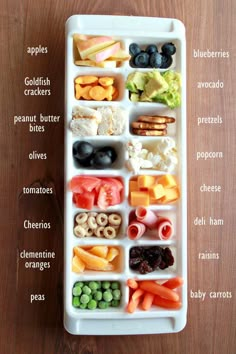 a white tray filled with lots of different types of food on top of a wooden table