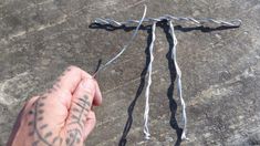 a hand holding a piece of barbed wire on top of a stone surface with the word love written across it