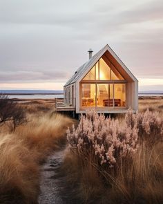 a small house sitting on top of a dry grass covered field next to the ocean