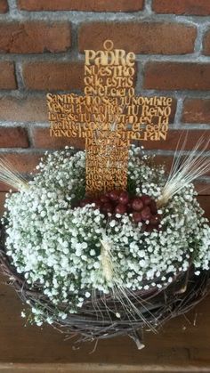 a cross is placed on top of a wreath with baby's breath in front of a brick wall