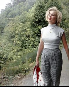 a woman is walking down the road with an umbrella in her hand and she has blonde hair