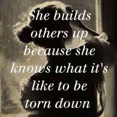 a woman standing in front of a window with the words, she build's others up because she knows what it's like to be torn down