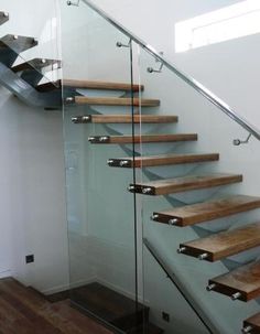 a glass stair case with wooden treads