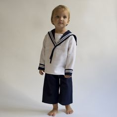 a young boy in sailor's outfit posing for the camera on a white background