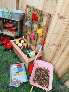 an outdoor garden area with gardening tools and pots on the ground next to a wooden fence