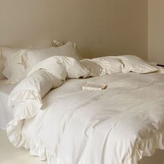 an unmade bed with white sheets and pillows