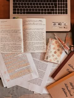 a laptop computer sitting on top of a desk covered in papers and writing utensils