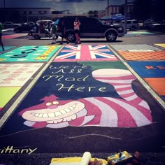 a woman standing in front of a car on a street painted with the words we're mad here