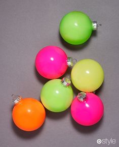 four neon colored ornaments on a gray surface