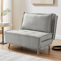 a gray couch sitting on top of a hard wood floor next to a white rug