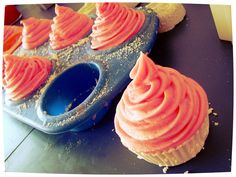 some cupcakes with pink frosting and sprinkles are on a blue tray