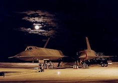 two fighter jets parked on the tarmac at night with a full moon in the background