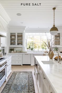 a large kitchen with white cabinets and an area rug on the floor in front of it