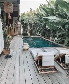 an outdoor swimming pool with lounge chairs and potted plants on the deck next to it